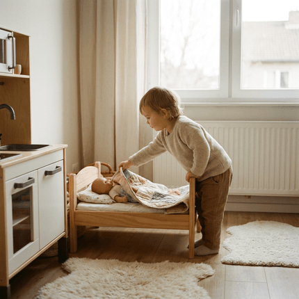 Houten poppenbedje met zacht beddengoed in een lichte kinderkamer, terwijl een peuter een pop instopt tijdens rustig fantasiespel.